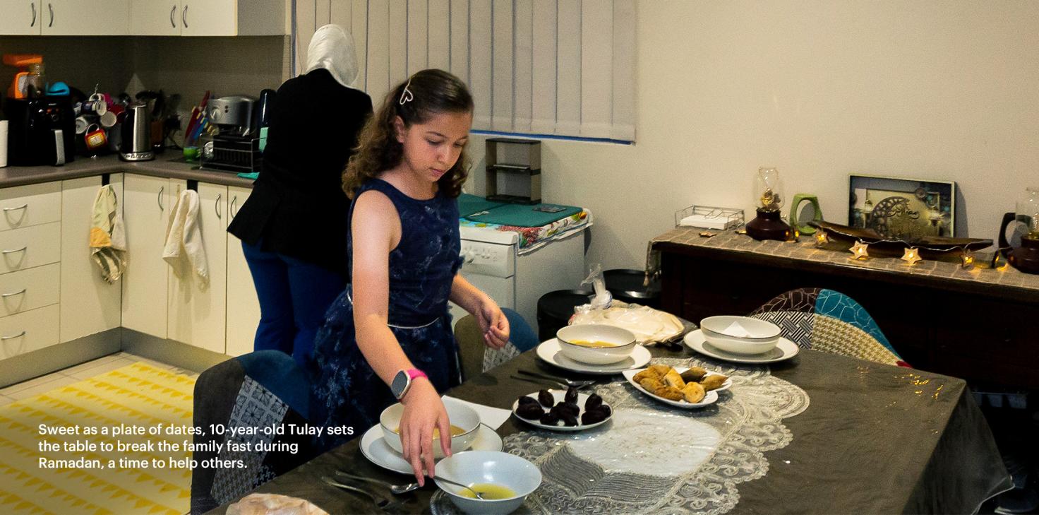 Sweet as a plate of dates, 10-year-old Tulay sets the table to break the family fast during Ramadan, a time to help others.